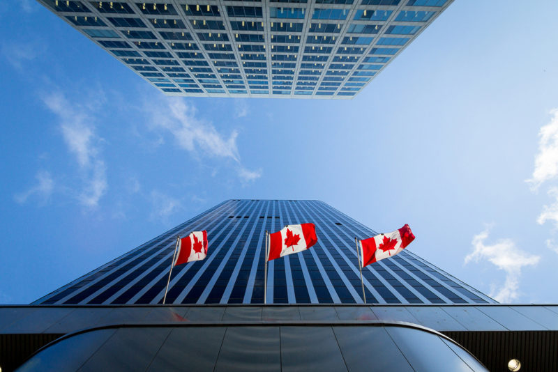 Three Canadian flags in front of a business building in Ottawa, Ontario, Canada. Ottawa is the capital city of Canada, and one of the main economic, political and business hubs of North America