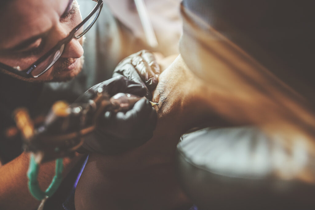 Men tattooing a person.